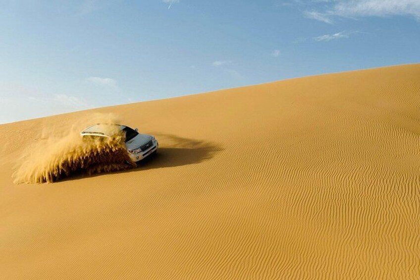 A vehicle driving through a desert with sand dunes. 3