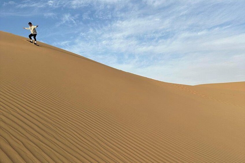 A person climbing a sand dune under a clear sky. 2