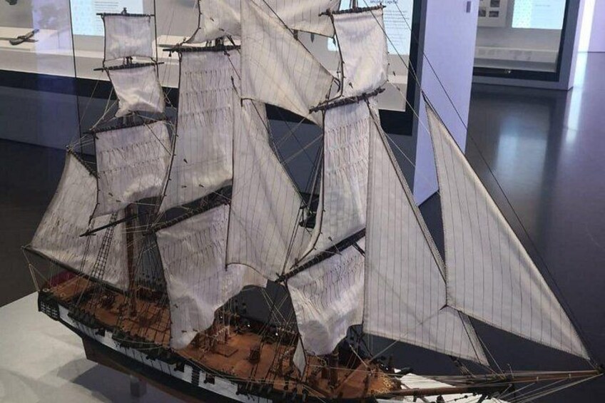 A detailed model of a sailing ship with multiple sails, a wooden deck, and a figurehead. 5