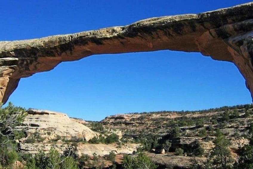 A natural rock arch formation with a clear blue sky. 2