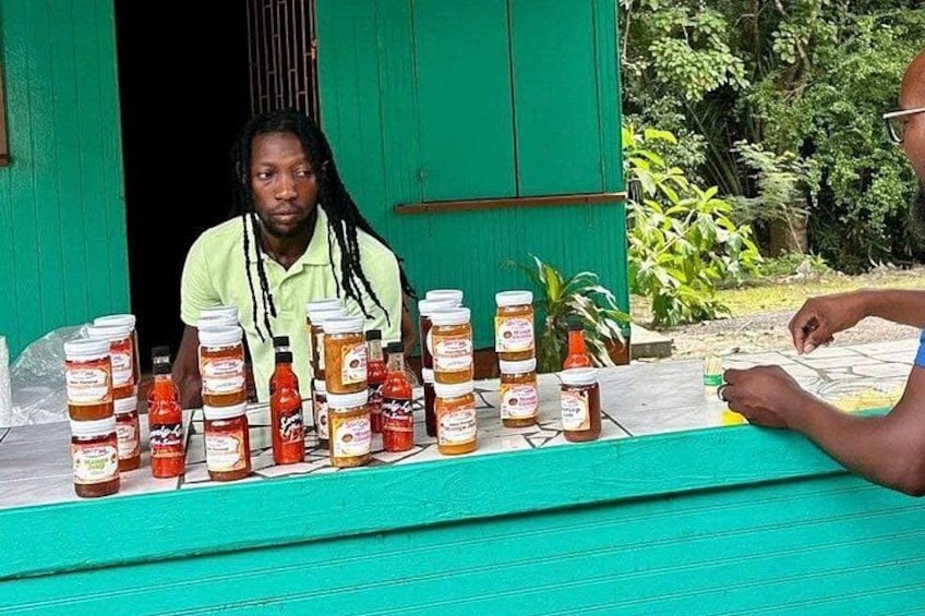A person sitting at a table with jars of honey and honeycomb. 5