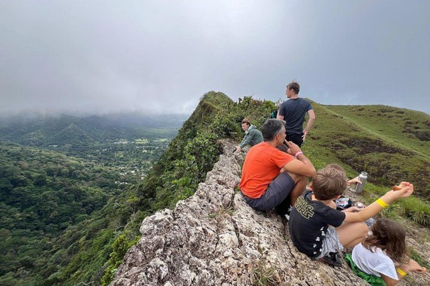 People sitting on a rocky ledge overlooking a valley. 3