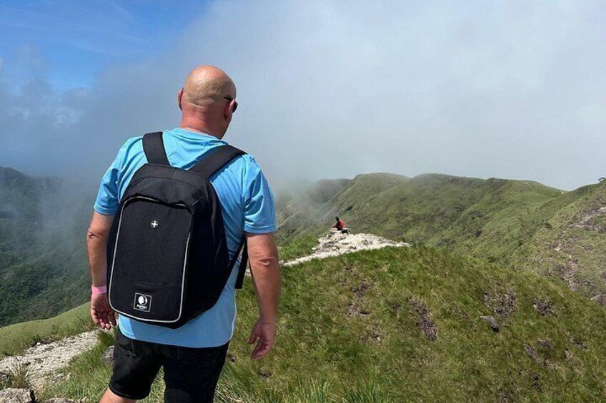 A person with a backpack on a grassy hill with a hiker in the distance. 4