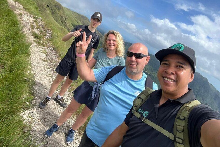A group of people hiking on a rocky trail with mountains in the background. 2