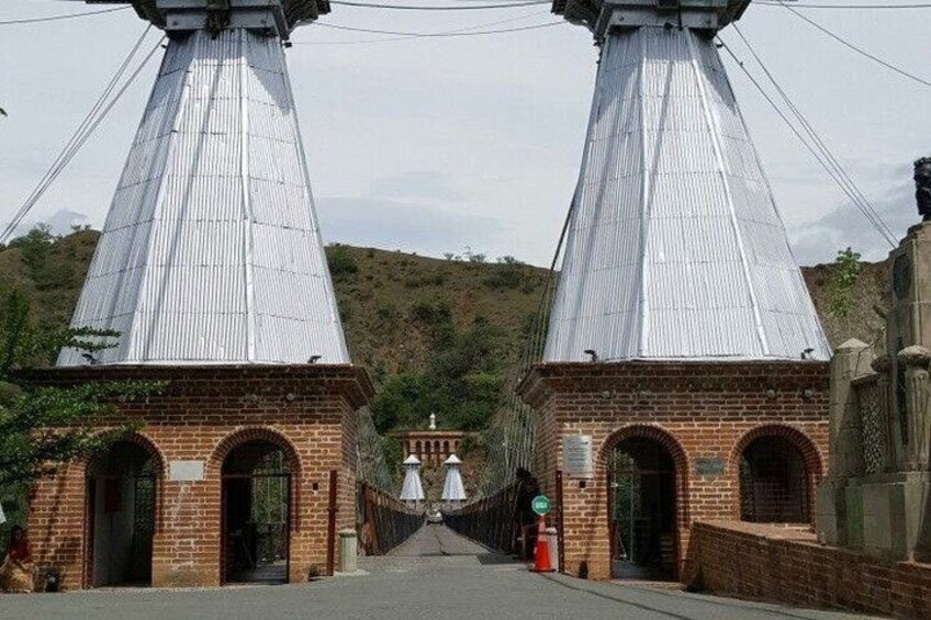 A bridge with two large metal towers and brick buildings at each end. 3