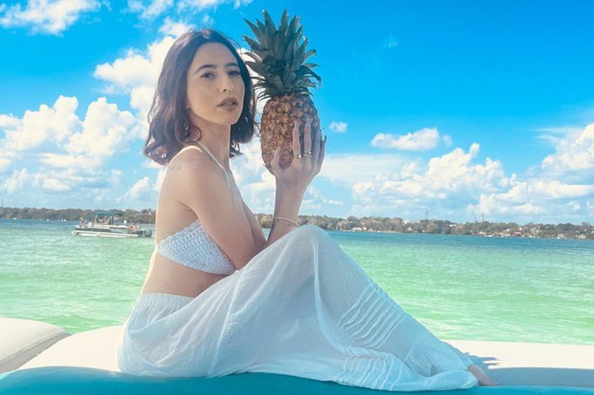 A person sitting on a boat holding a pineapple. 2