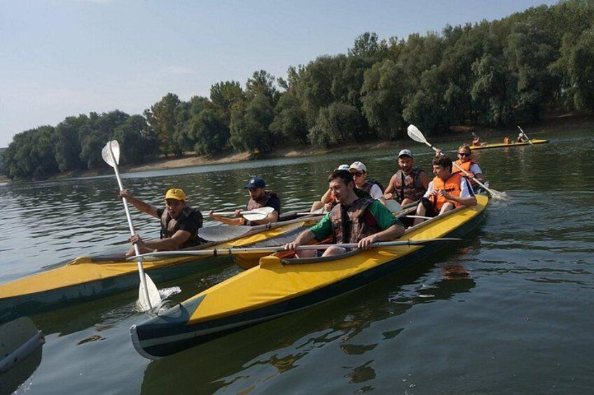 A group of people in canoes on a calm river, surrounded by trees. 4