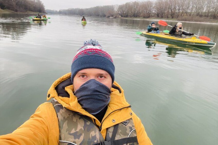 A person kayaking on a river with other kayakers in the background. 3