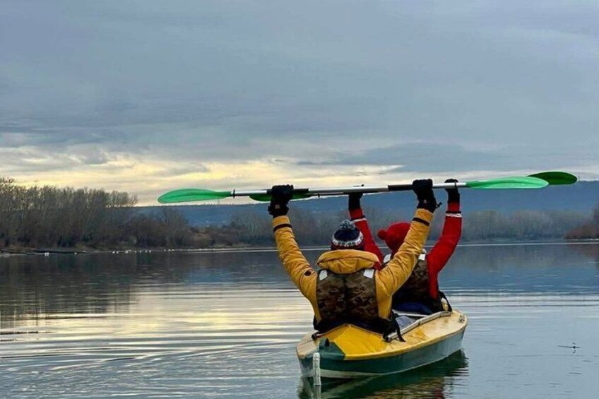 A person in a kayak holding a paddle over their head. 2