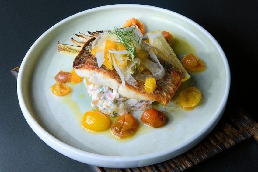 A plate of food with a fish fillet, vegetables, and a sauce. 2