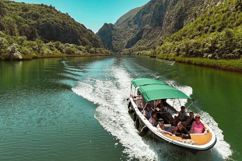 A boat with passengers on a river surrounded by lush greenery and mountains. 2