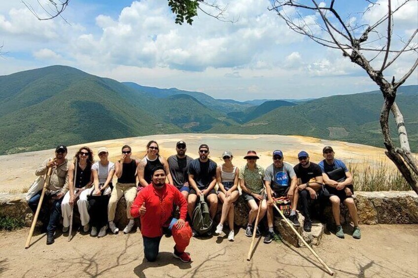 A group of people sitting on a ledge with a mountainous landscape in the background. 5