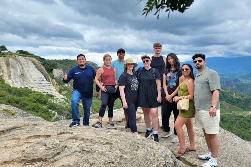 Un groupe de personnes se tient sur un promontoire rocheux, avec un paysage montagneux en arrière-plan. 1