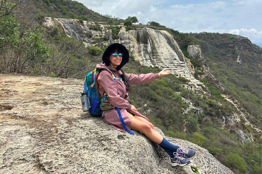 Une personne assise sur un promontoire rocheux, un sac à dos sur le dos, et qui contemple un paysage montagneux. 2