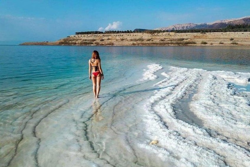 A person walking in a salt flat with clear water and white salt formations. 3