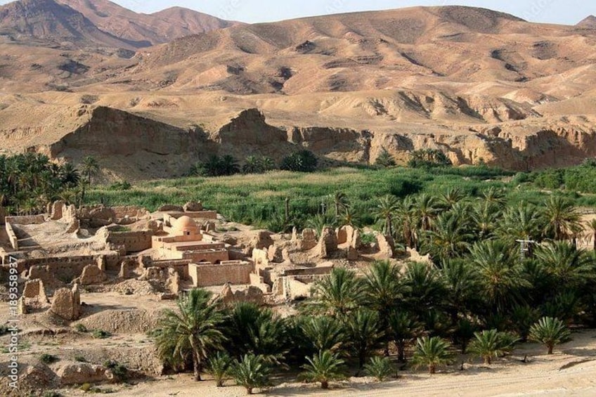 Ancient ruins with palm trees in the foreground and a desert landscape in the background. 3