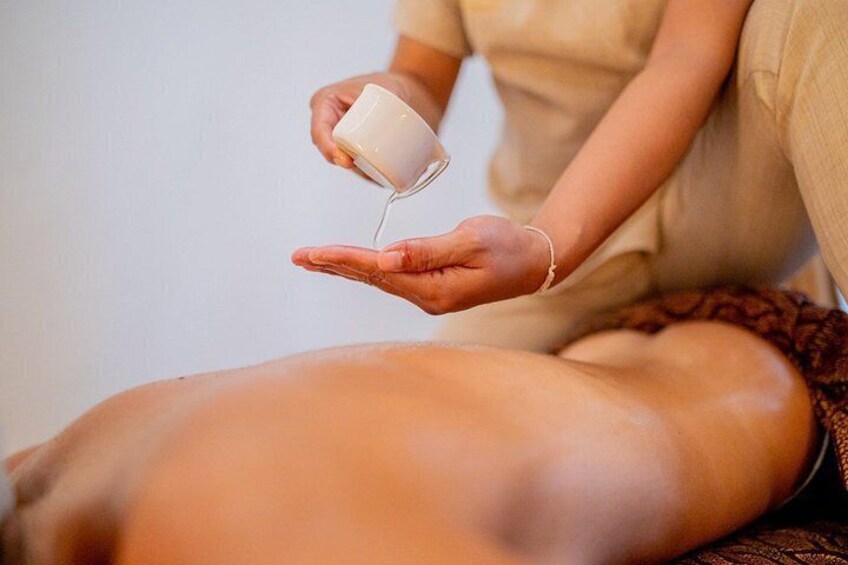 A person holding a cup, pouring liquid onto another person's leg. 3
