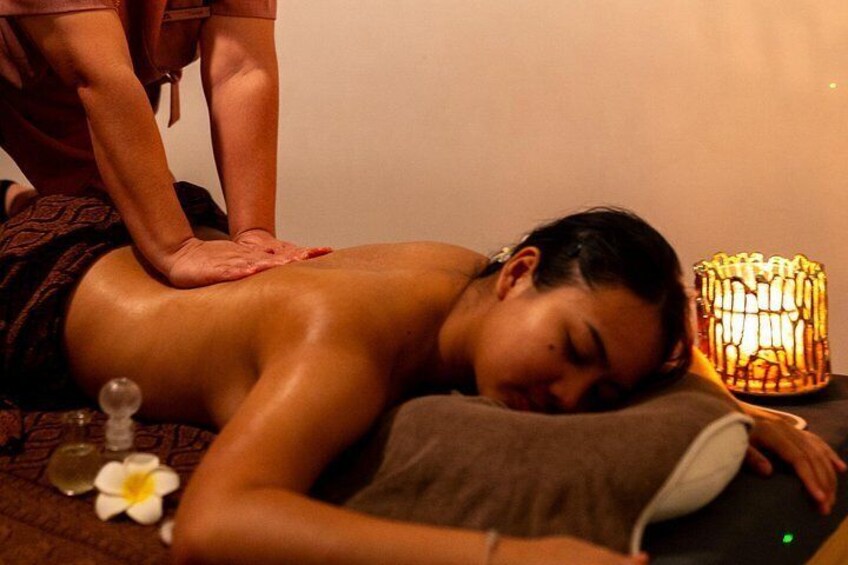 A person receiving a massage, a candle, and a flower on the floor. 4