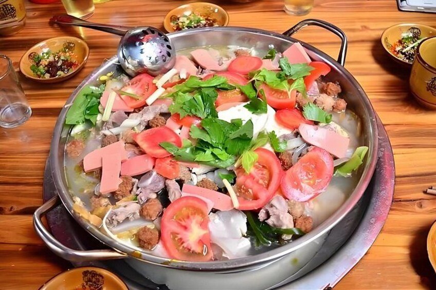 A hot pot with various meats, vegetables, and a ladle. 3