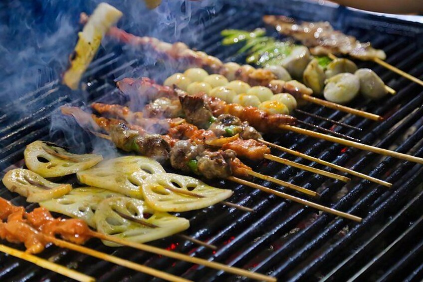 A variety of skewers and grilled vegetables on a grill. 2