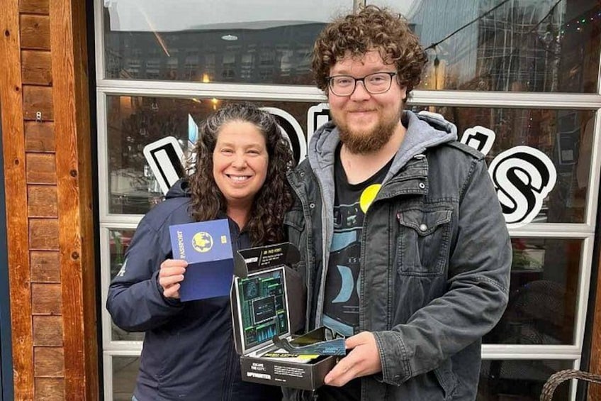 Two people holding a passport and a device in front of a store window. 3