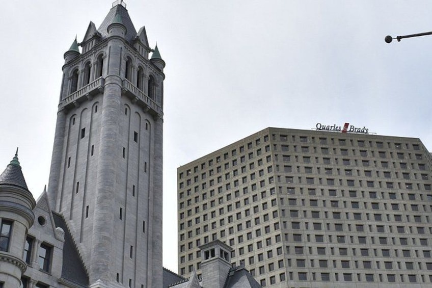 A historic tower and a modern building with the Quarles Brady logo. 2