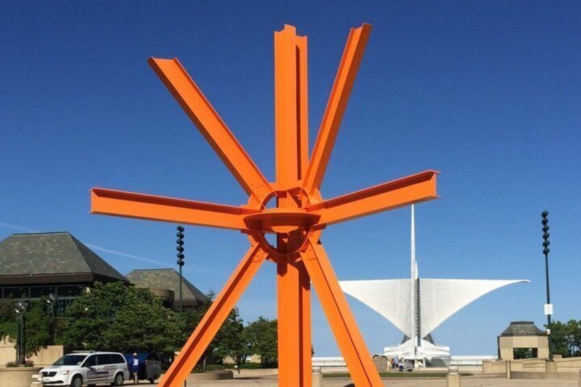A large orange sculpture with a central circular element, surrounded by a clear blue sky. 2