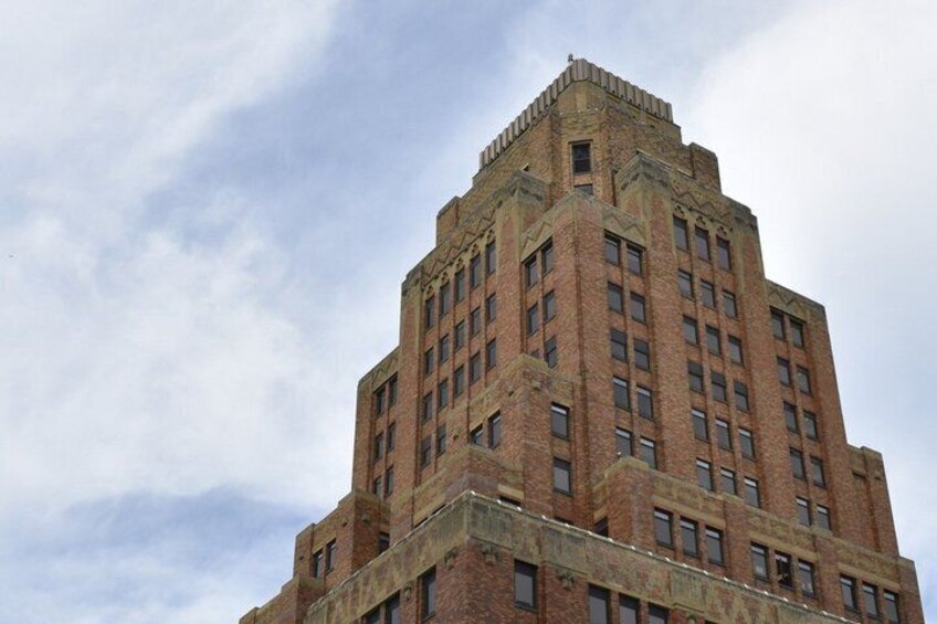 A tall brick building with a distinctive corner turret and multiple windows. 4