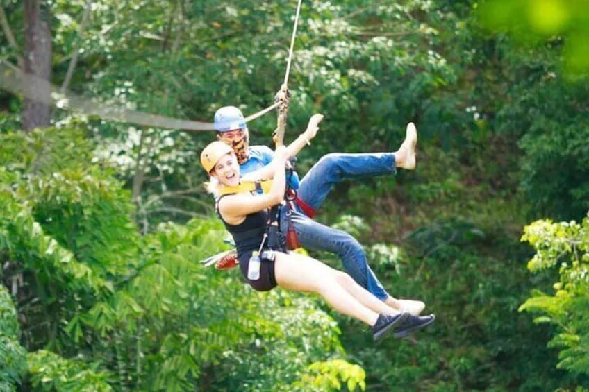 Two people zip-lining through a forest. 2