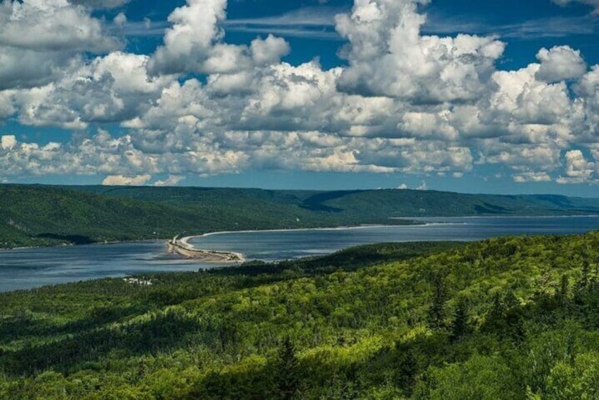 A coastal landscape with a winding river, dense greenery, and a distant shoreline. 1