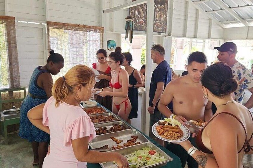 A buffet with various food items and people serving and eating. 4