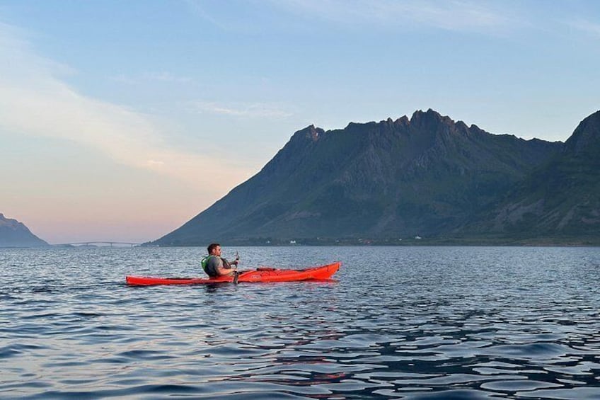 A person kayaking on calm water with mountains in the background. 3