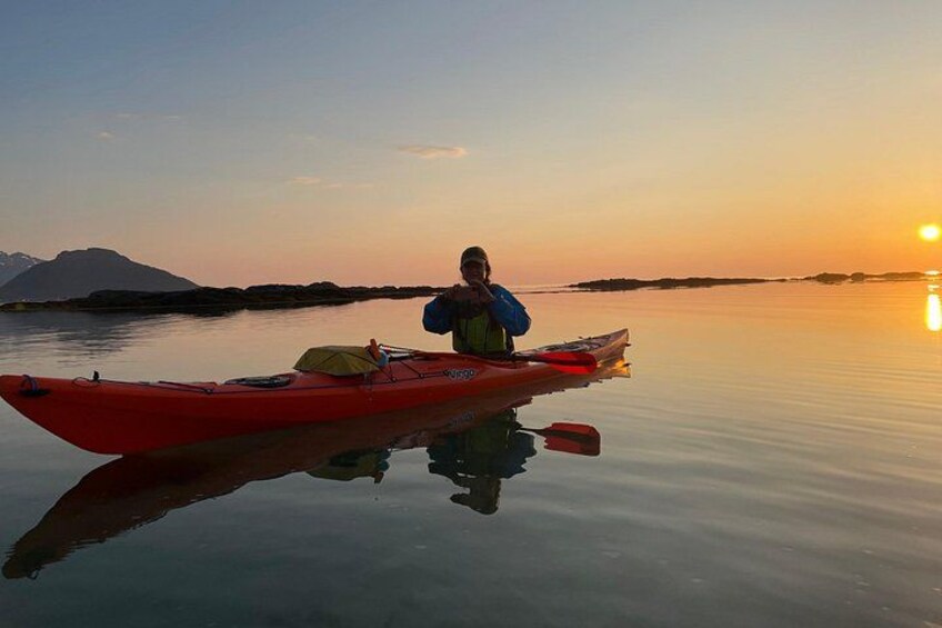A person in a red kayak on calm water during sunset. 1