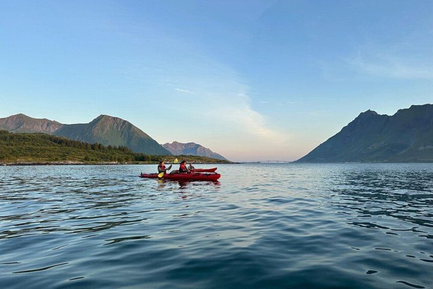 A calm lake with kayaks, mountains in the background, and a clear sky. 2