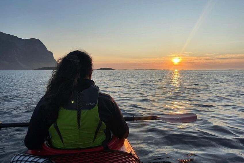 A person kayaking on calm water during sunset with a mountainous landscape in the background. 2