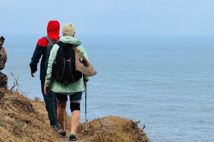 Dos personas caminando por una costa rocosa con una masa de agua al fondo. 2