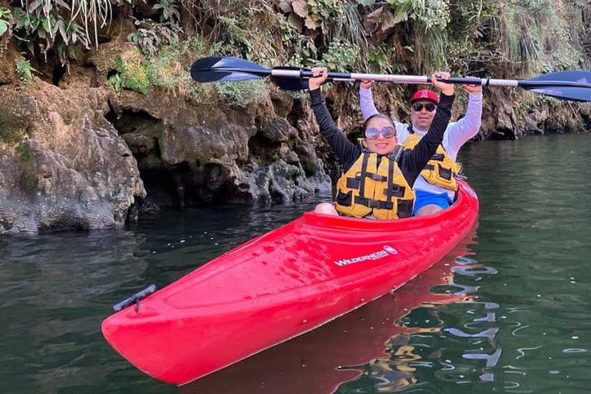 A red kayak with two people wearing life jackets on a calm river. 4