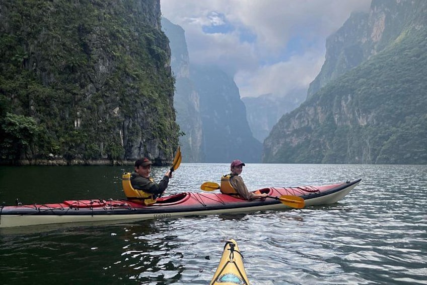 Two people kayaking on a calm river surrounded by steep cliffs. 5