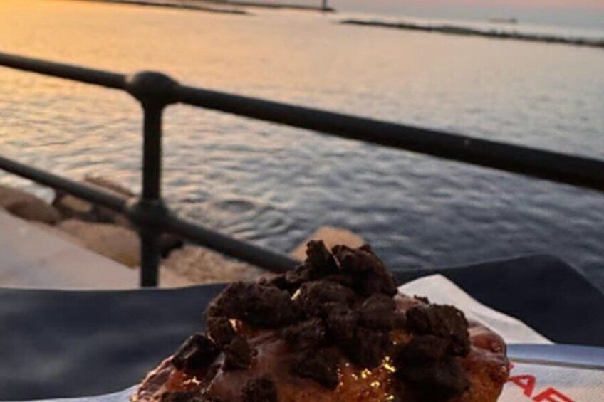 A close-up of a food item with a dark topping, possibly a dessert, on a surface with a metal railing in the background. 3