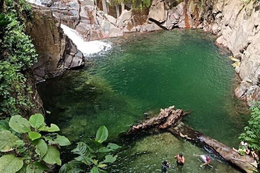 A clear green pool surrounded by rocky terrain and vegetation. 4