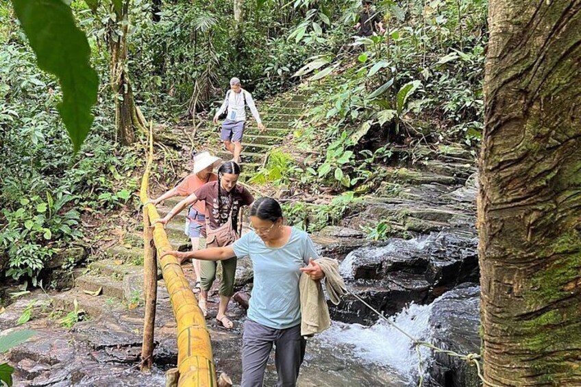 People crossing a rocky stream using a makeshift bridge. 2