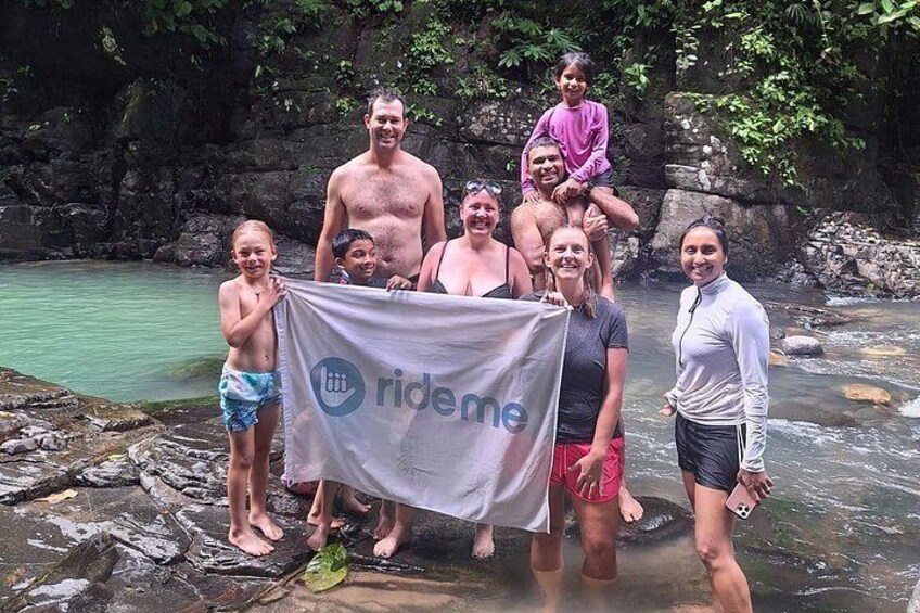 A group of people standing by a river with a banner. 3