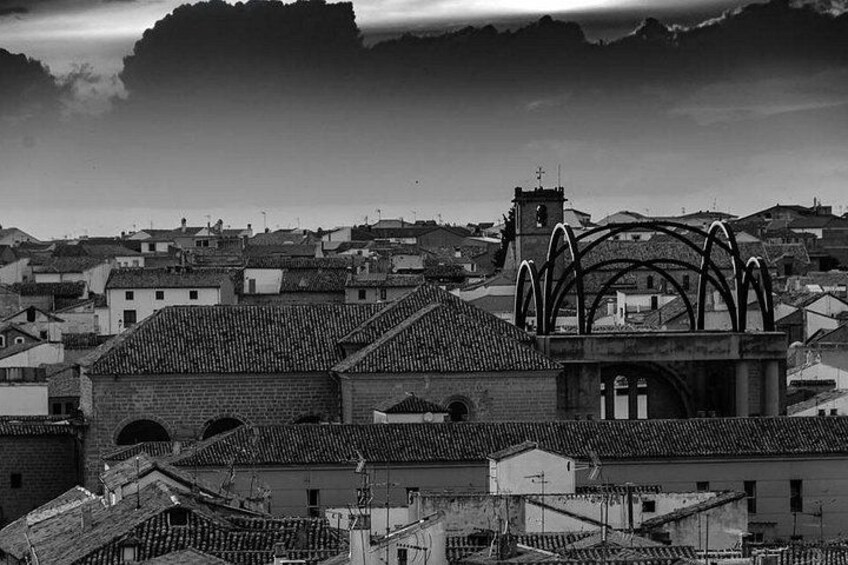 Una vista en blanco y negro de un pueblo con una iglesia destacada, con estructuras de arcos y un campanario. 4