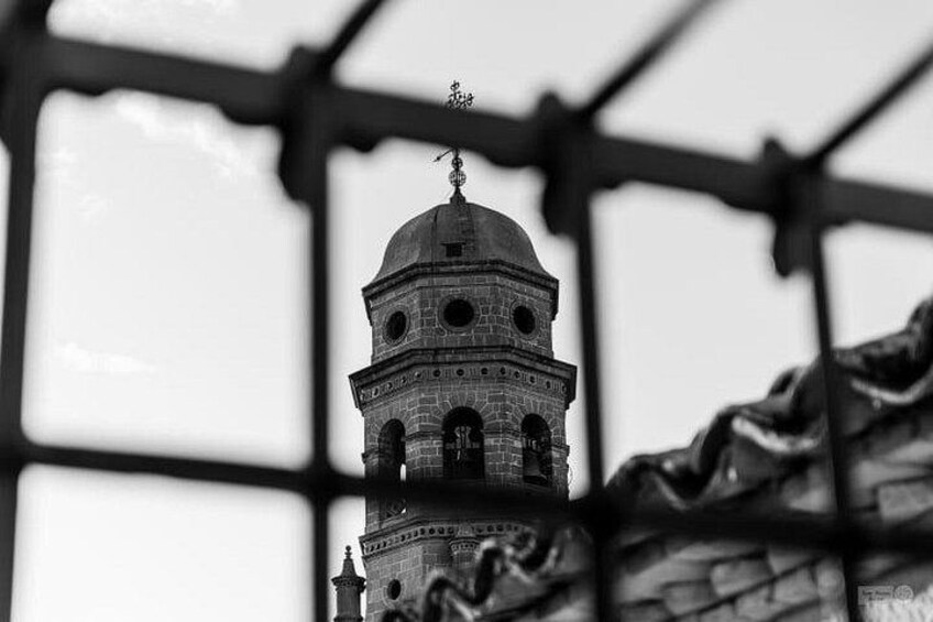 Una torre abovedada con veleta, rodeada por una cerca de metal. 3