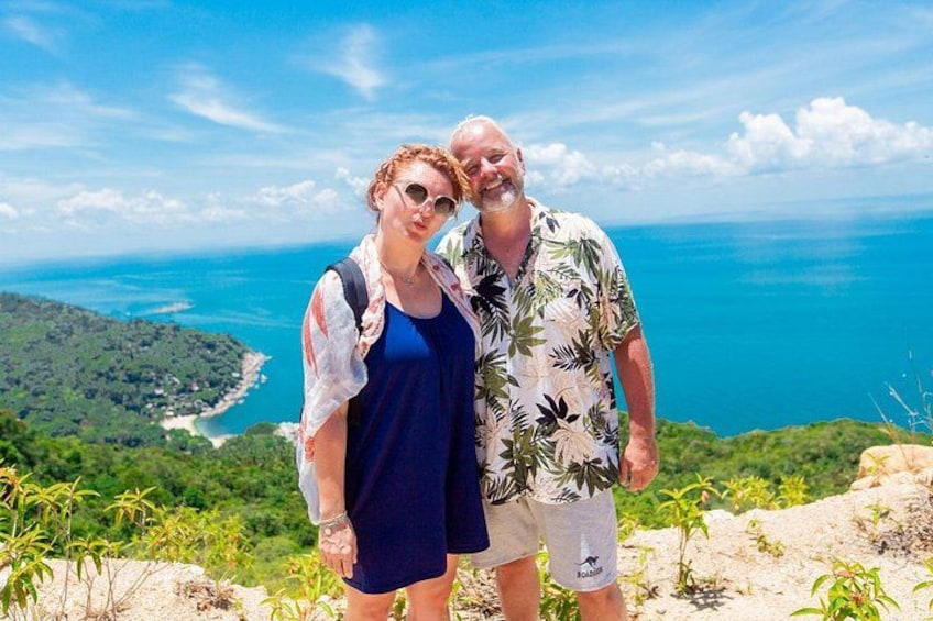 A couple standing on a cliff overlooking a coastal landscape with a view of the ocean and a distant shoreline. 3