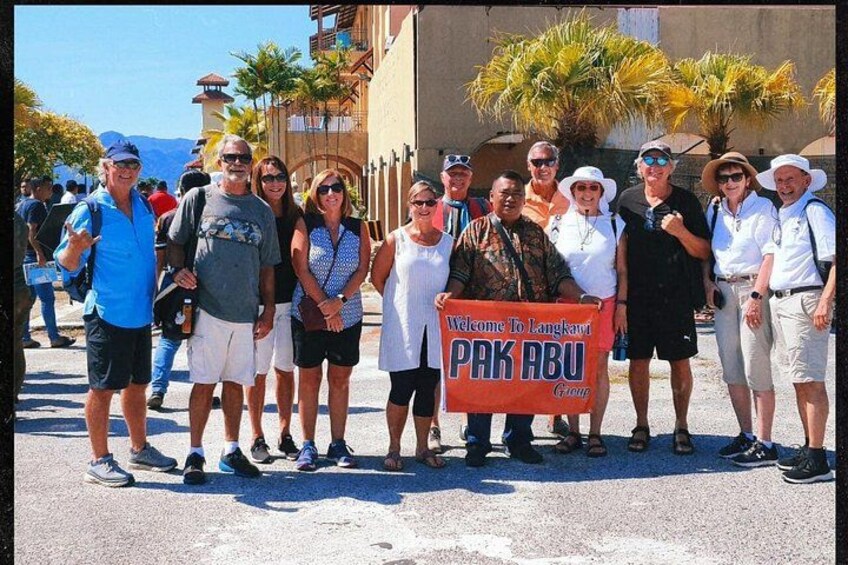 Eine Gruppe von Menschen hält ein Schild mit der Aufschrift 'Welcome to Langkawi, PAKABU'. 2