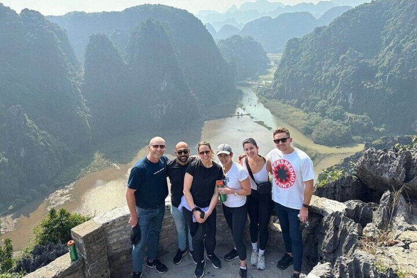 A group of people standing on a stone platform overlooking a river valley with steep cliffs. 4