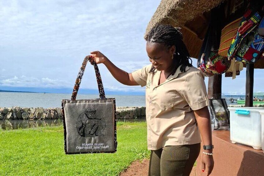 A person holding a bag with a giraffe design, standing near a thatched-roof structure by a body of water. 5