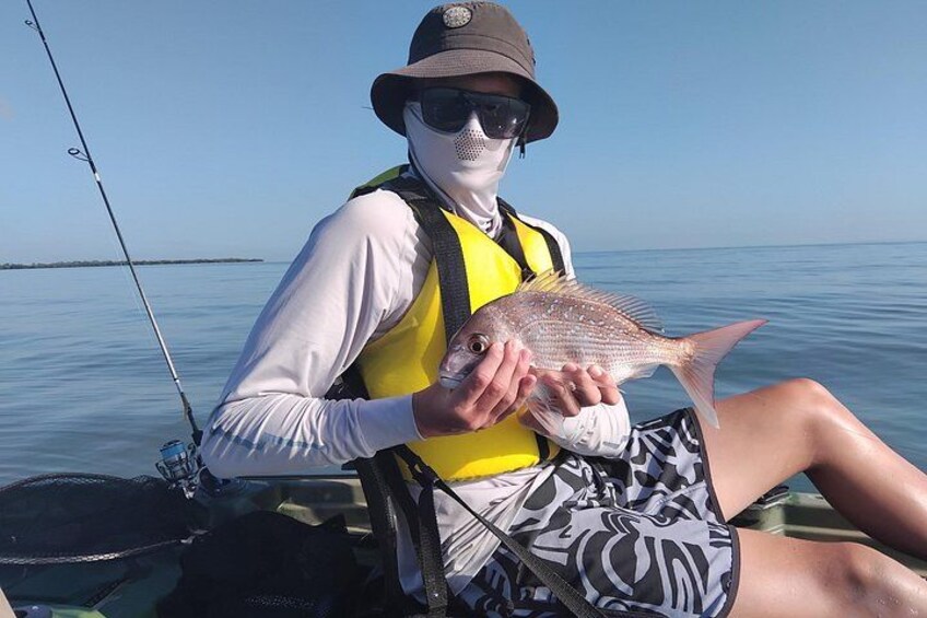 A person holding a fish on a boat. 5