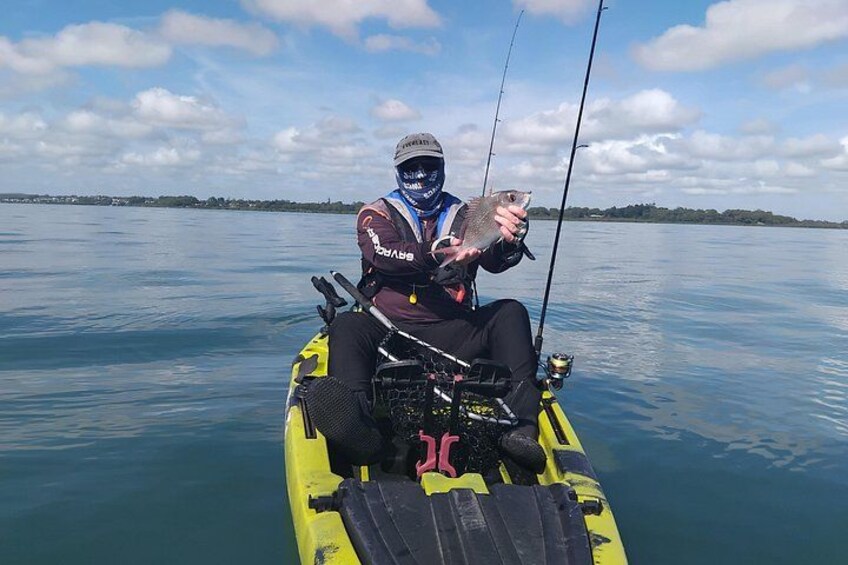 A person fishing on a yellow kayak in calm water with a clear sky. 2